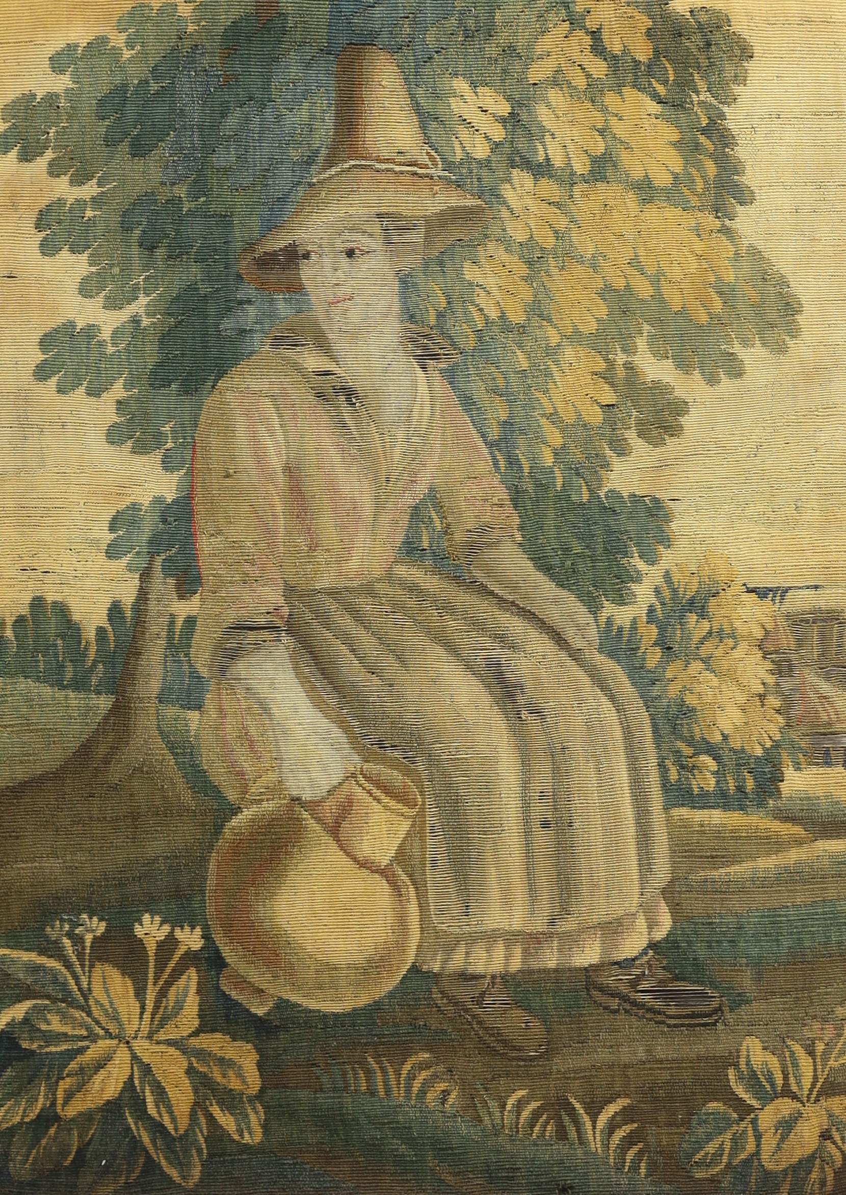 Two 18th century Brussels verdure tapestry panels, one of a seated peasant lady holding a flagon and the other a similar gentleman holding a large tankard, surrounded by lush green landscape, probably part of a larger ta